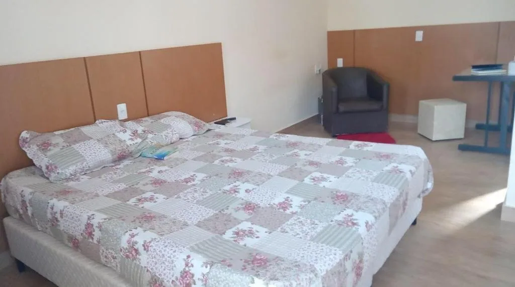 Suíte com cama de casal, poltrona e mesa de trabalho