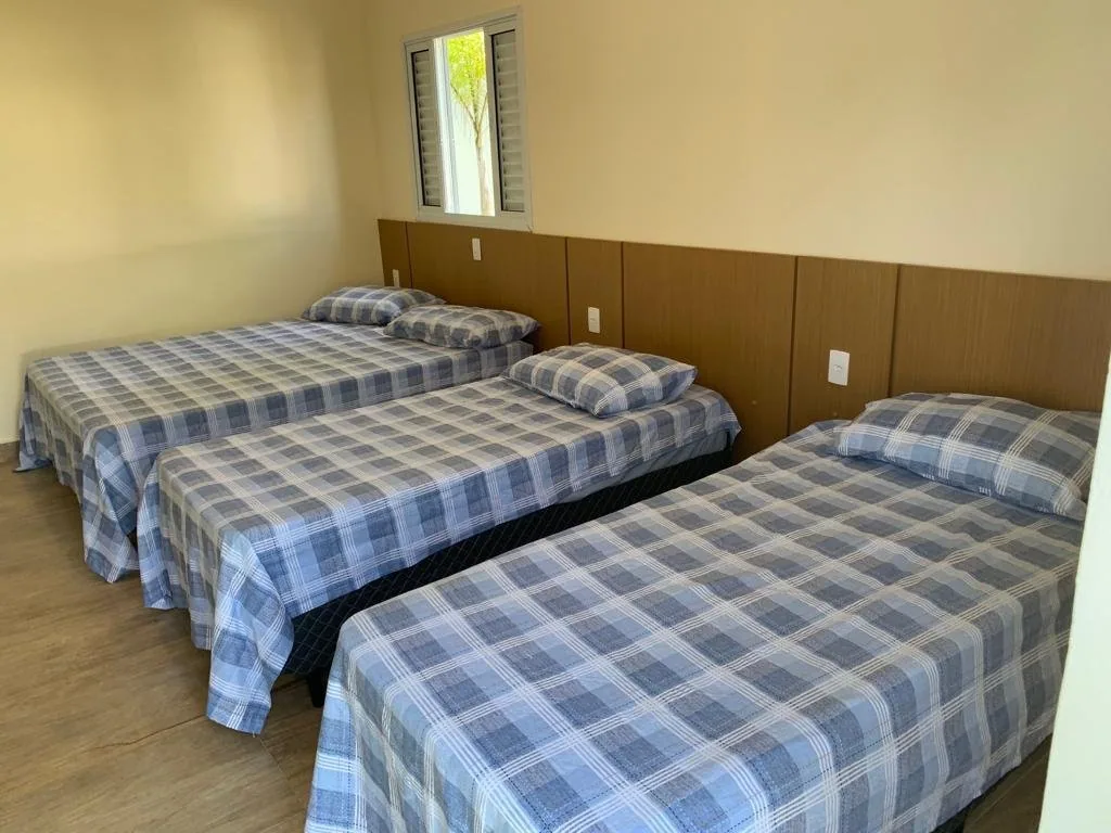 Quarto com três camas de solteiro e colchas xadrez