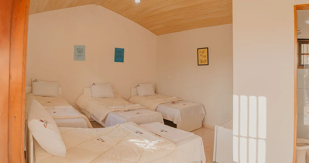Quarto com três camas de solteiro e forro de madeira