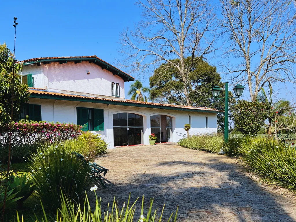 Casa principal branca com janelas verdes, caminho de pedra e jardim