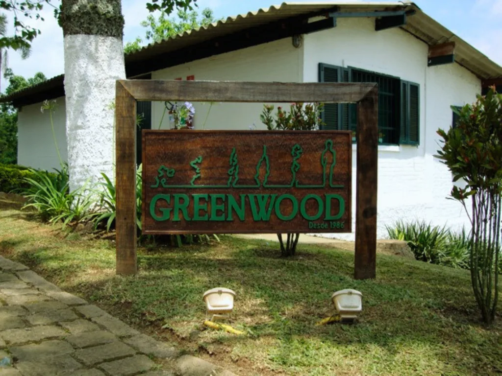 Placa de madeira com o nome Greenwood diante de uma casa branca
