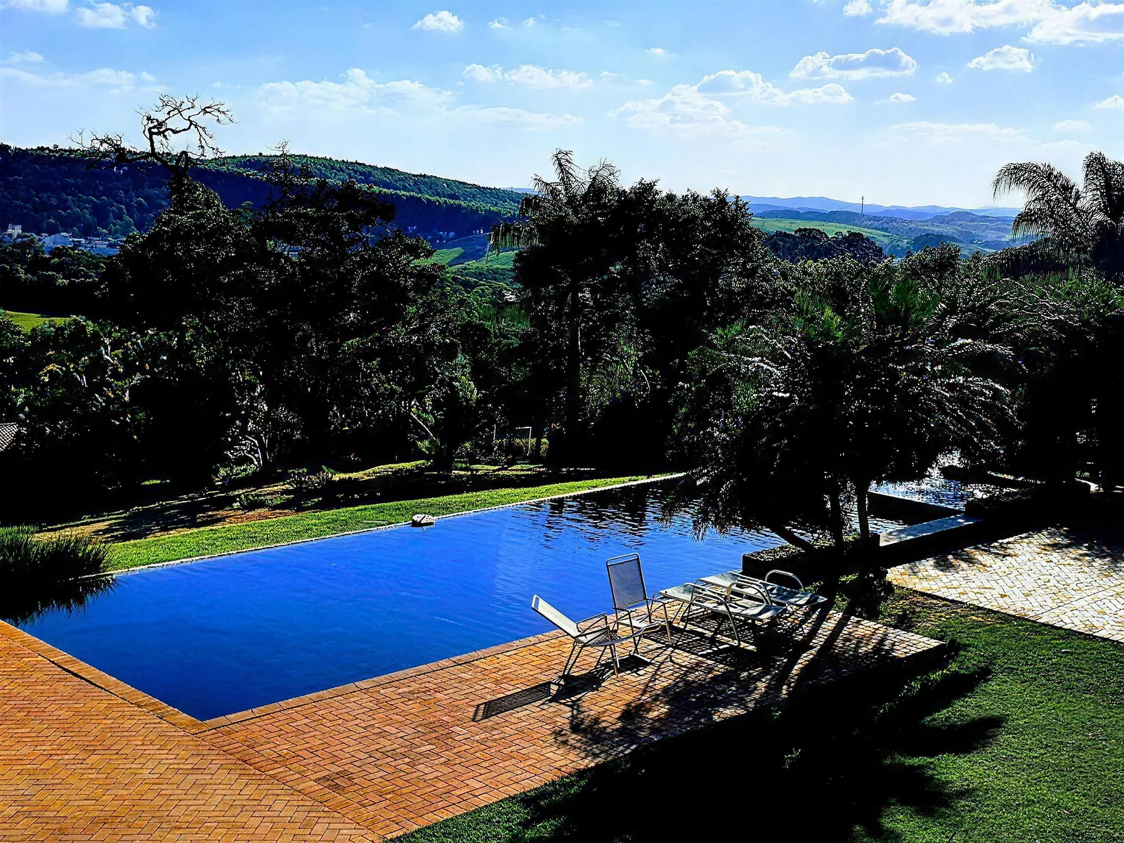 Piscina com borda voltada para o vale, cercada de mata