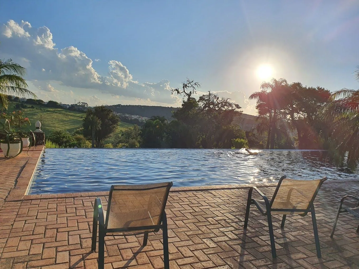 Deck da piscina ao pôr do sol, com a paisagem rural ao fundo