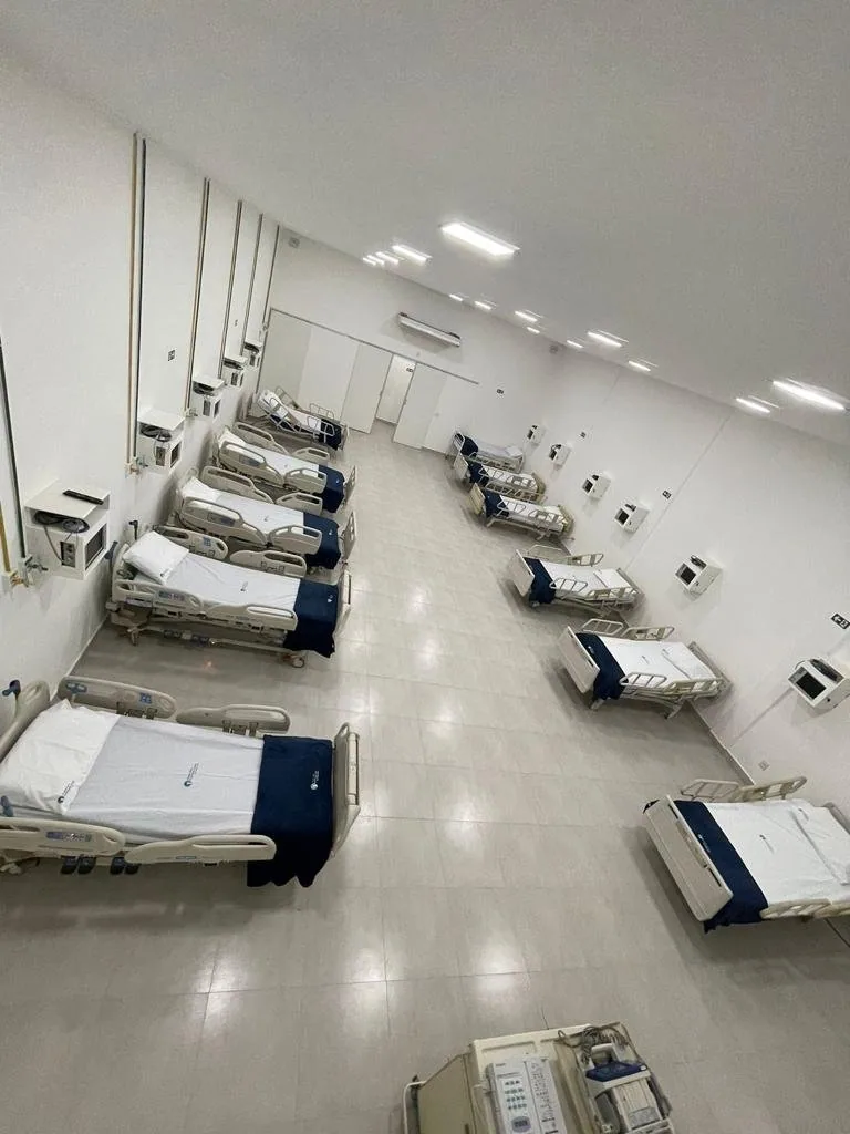 Corredor de enfermaria com duas fileiras de camas hospitalares