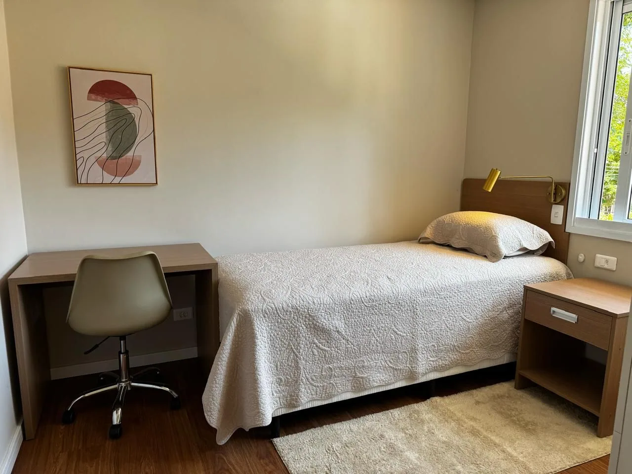 Quarto individual com cama de solteiro, escrivaninha e janela