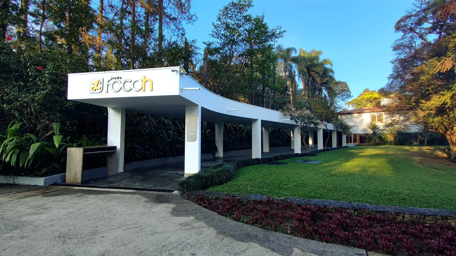 Portal de entrada da Rede Focoh, com cobertura branca e gramado ao fundo